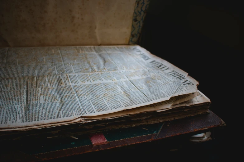 an open book on top of an old suitcase