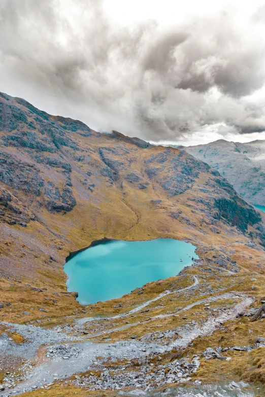 a big blue lake surrounded by mountains and clouds