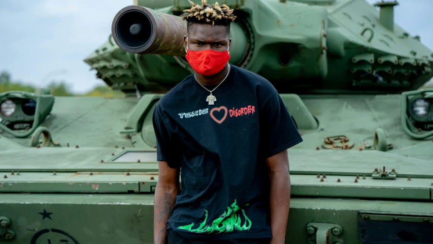 a man with a red mask standing in front of a tank