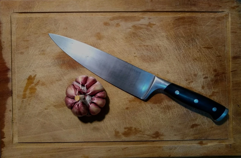 a sharp knife that is sitting on top of a  board