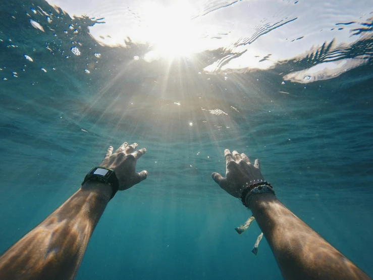 a pair of hands extending to the surface with clear water