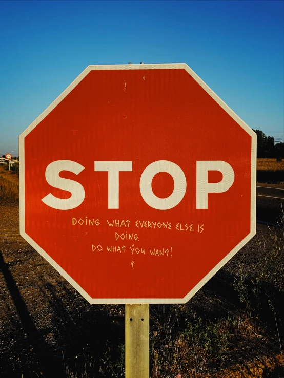 a stop sign on the side of the road with a message written on it