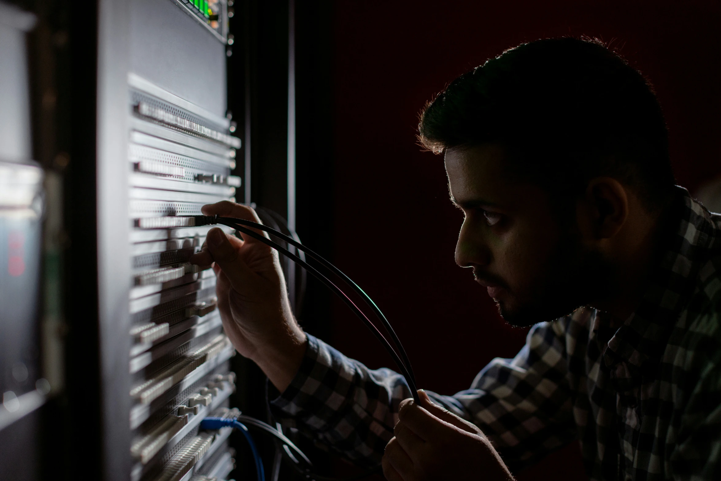 a man in a checkered shirt looking at electrical wiring