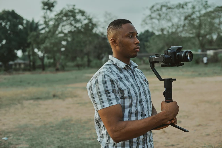 a man holding up his tripod in a field