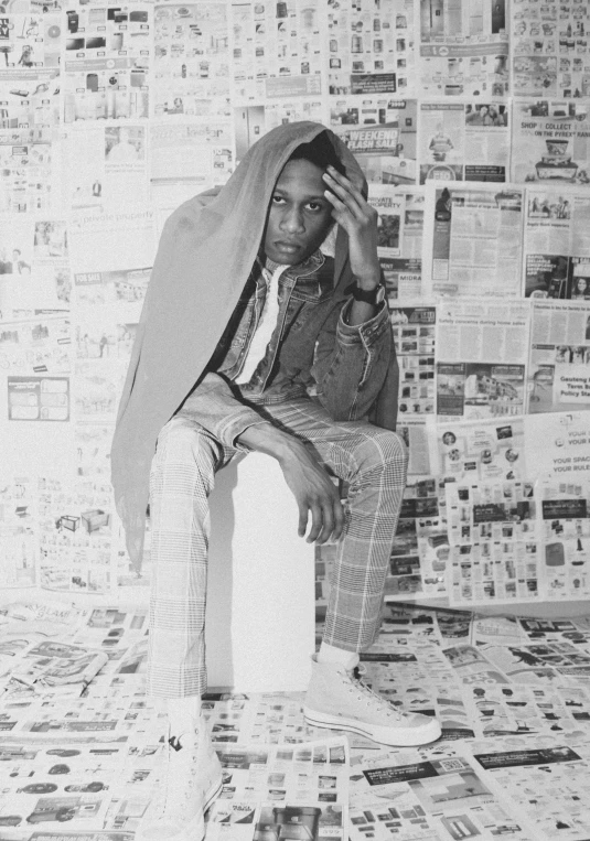 a man in a coat and tie sitting on a piece of newspaper