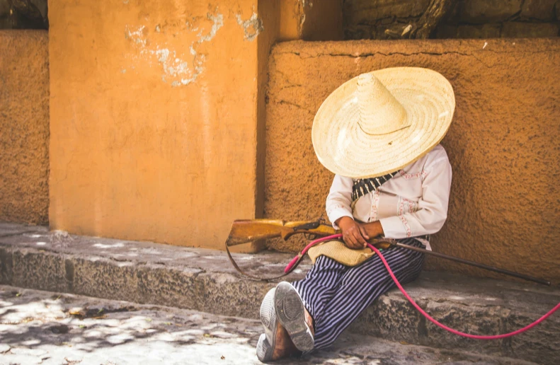 a person sitting on stairs with a straw hat and string