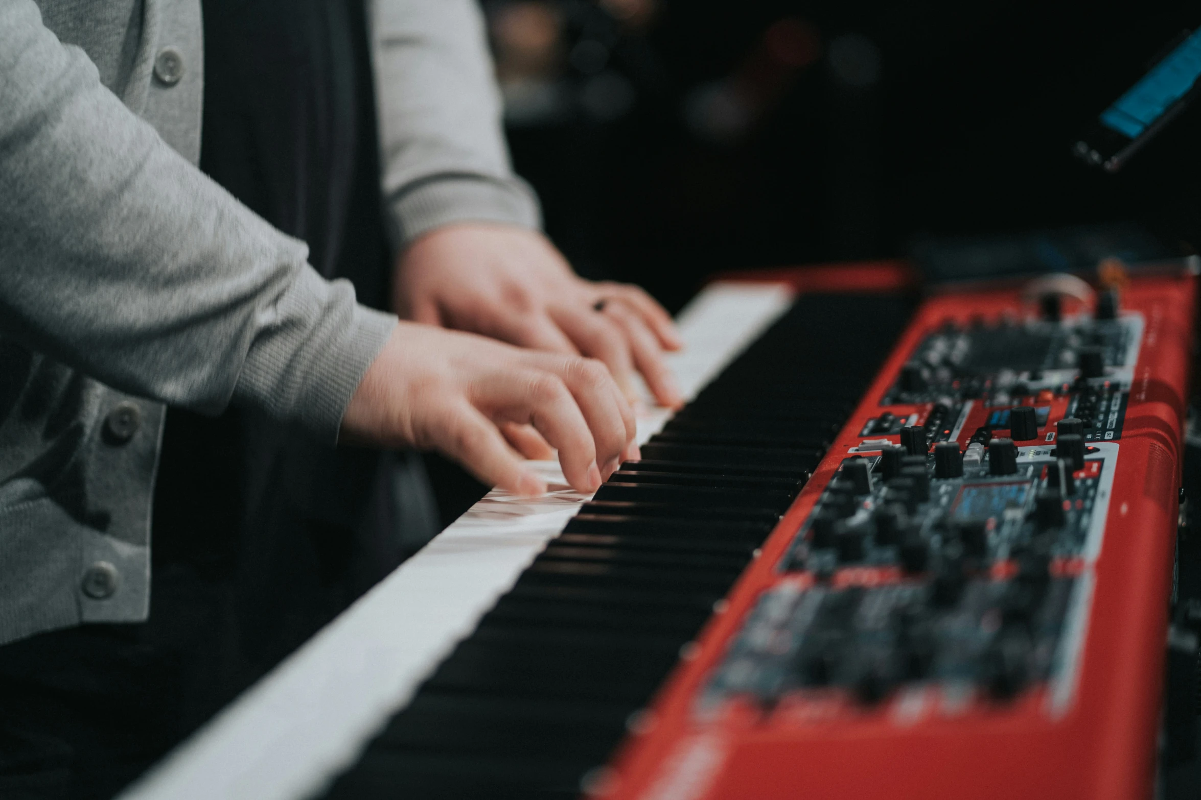 hands of two people playing on an electric keyboard