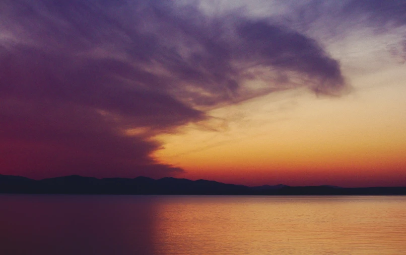 a cloud in the distance above a lake