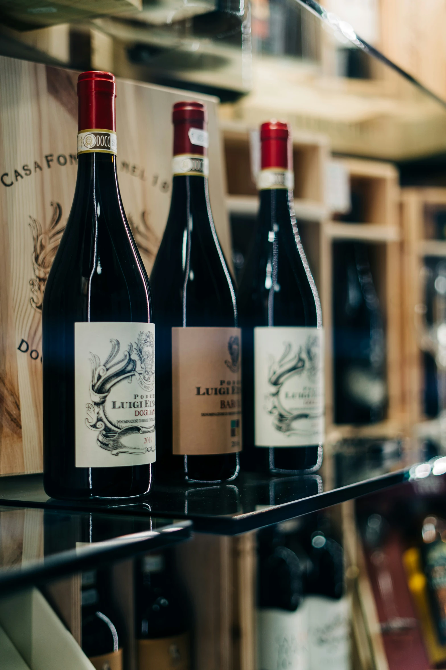 three wine bottles and glasses of wine on a counter