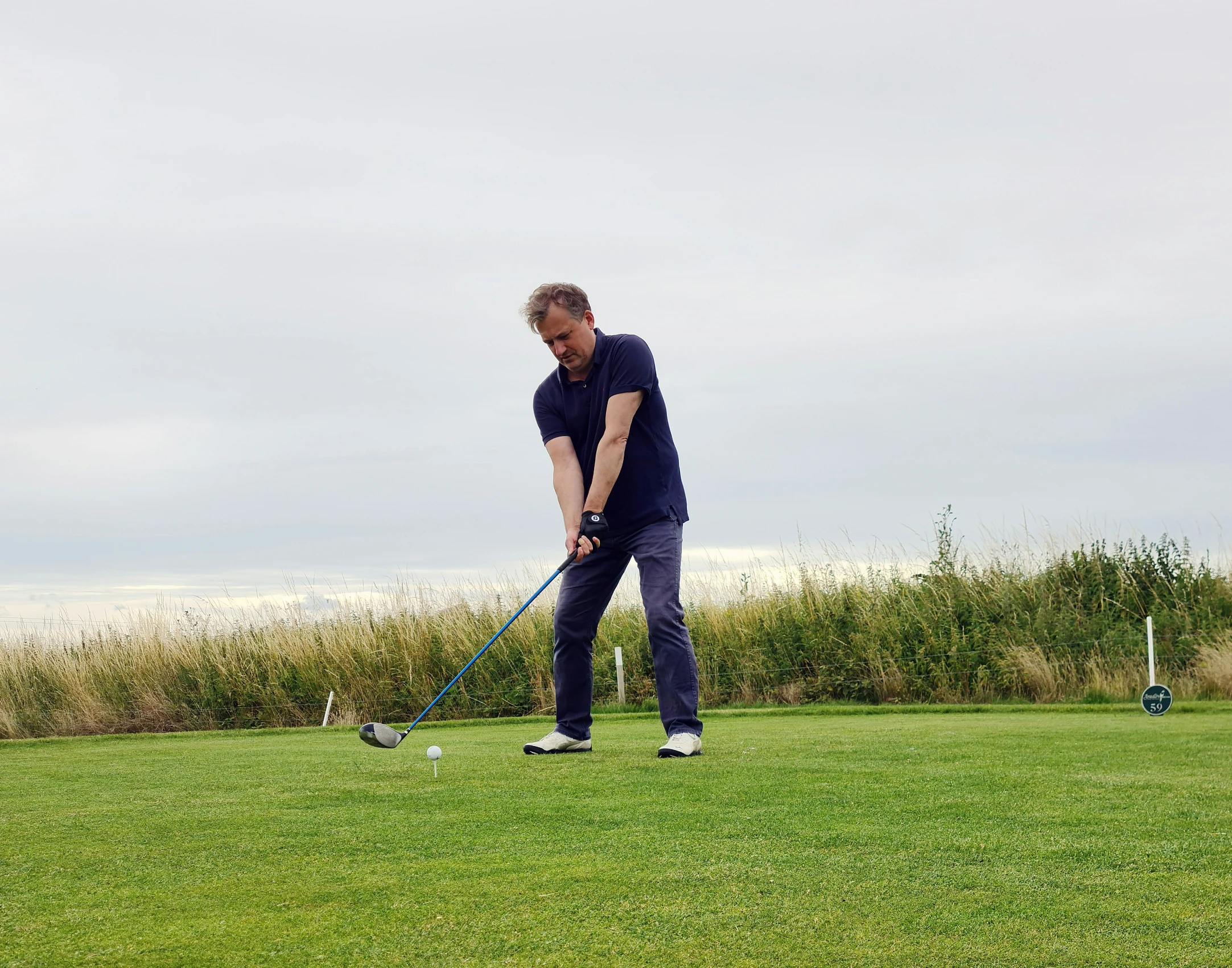 man wearing jeans playing golf in a field