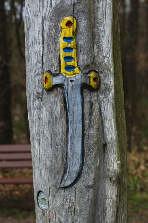 a handmade wooden knife mounted to the side of a tree