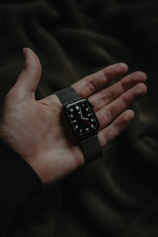 a person's hand with a watch on it and dark background