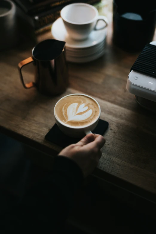 a person is holding a cup of coffee on a table