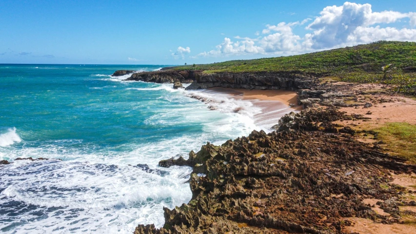 a sandy beach with a cliff and crashing waves