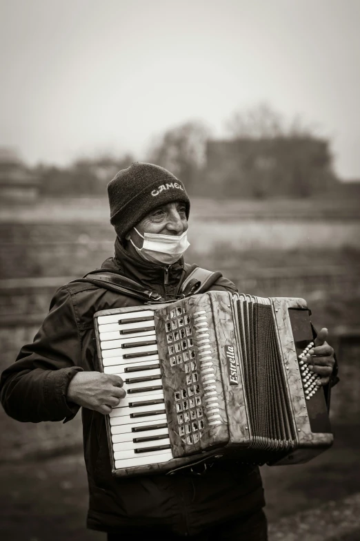 an old man with a mustache and a mouth mask playing an accordion