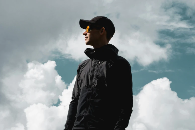 a man with sunglasses stands in the clouds