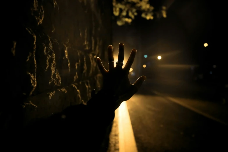 someone's hand reaching for the camera in front of a stone wall