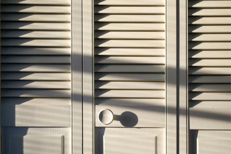 a white door with two metal knockholes and a white wall