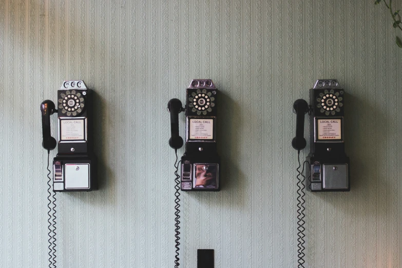 four old fashioned cellphones are hanging on a wall