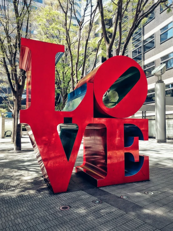 a large metal love sign sitting next to trees