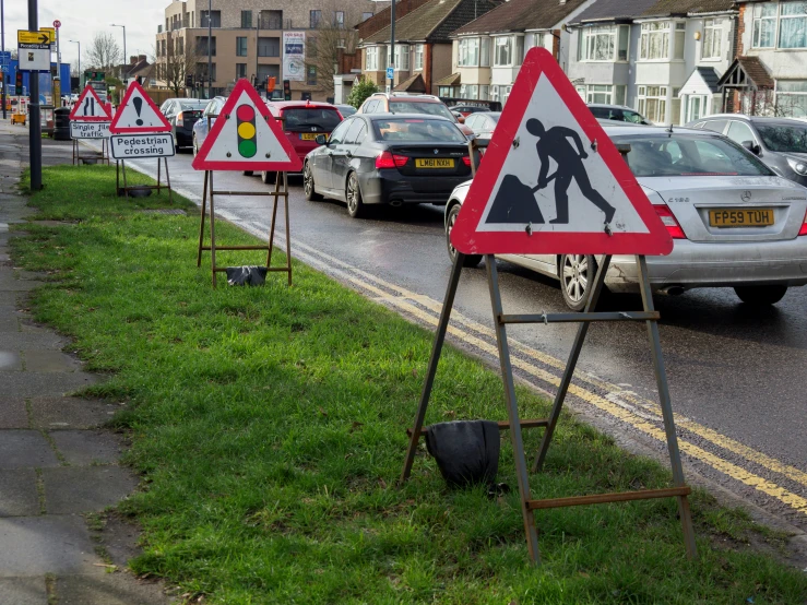 cars driving down a city road next to construction signs