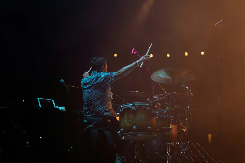 a man in blue shirt playing on a drum set