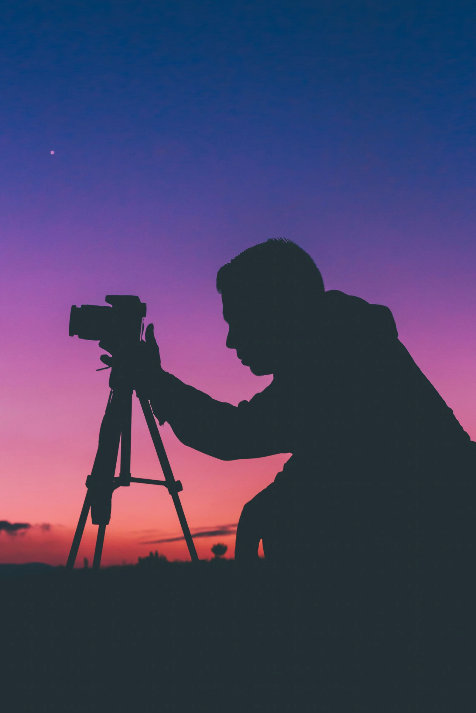 a man using a telescope to capture a sunset