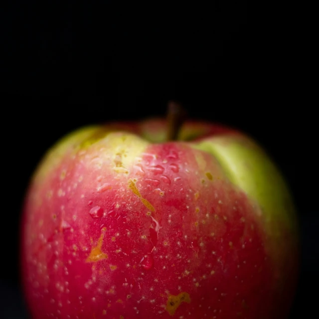 a red and yellow apple with a few drops of liquid