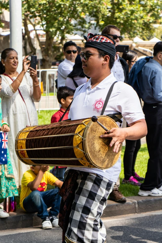 a man walking along the street holding a large drum