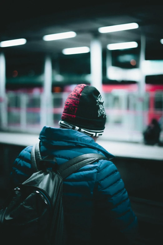 a person in a blue jacket waiting at the train station