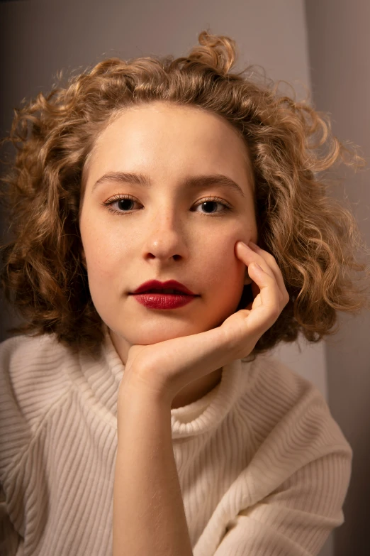 a young lady is wearing a sweater, she looks into the camera with a serious face