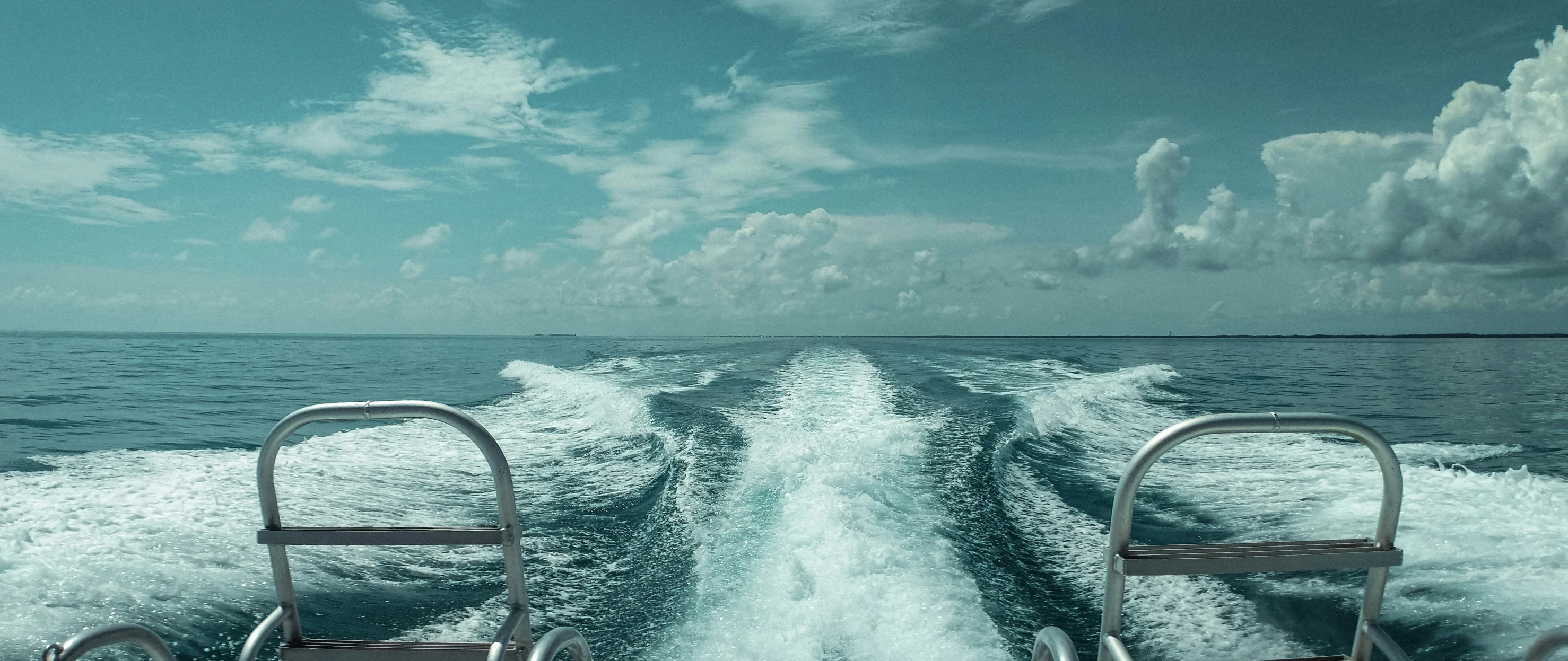 two motor boats moving along the water with white foam