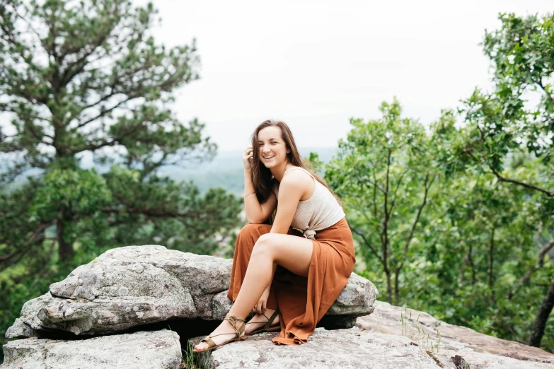 a woman is sitting on rocks smiling for a picture