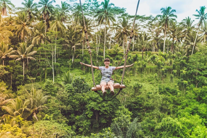 a person suspended on some wires above trees