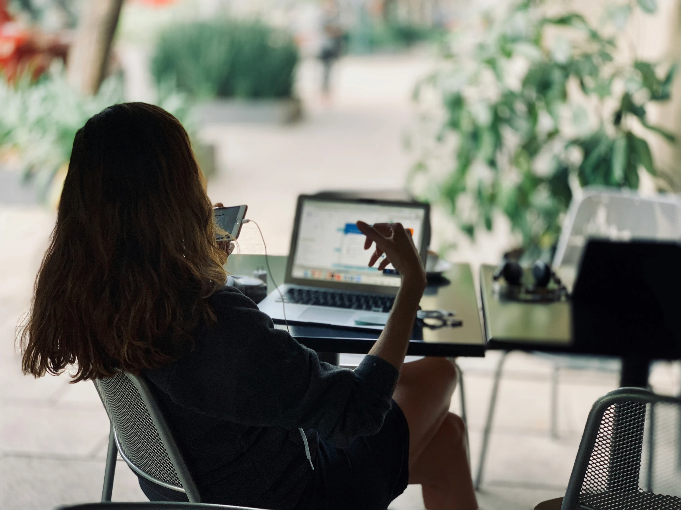 a woman is sitting on an outdoor chair using a laptop