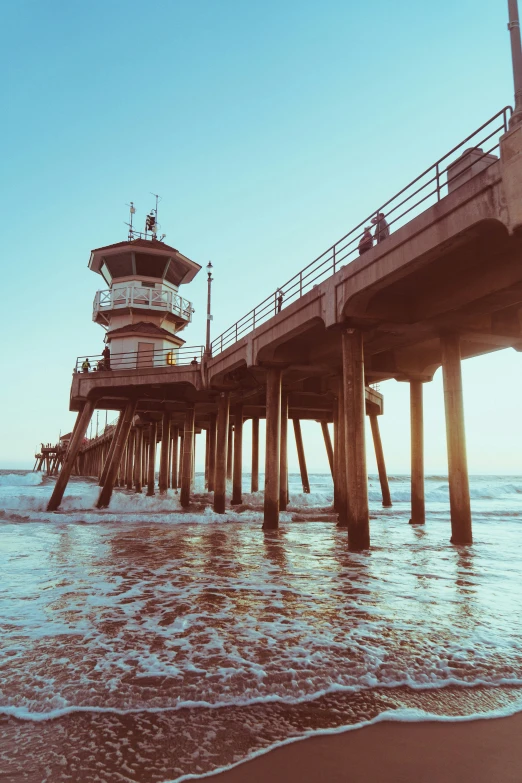 the beach is near a pier and a tall tower