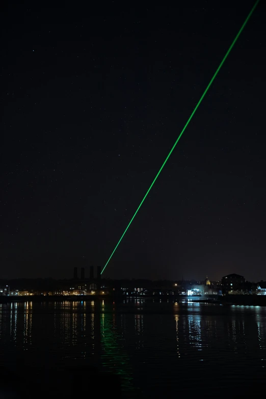 there is a green laser above water with a building