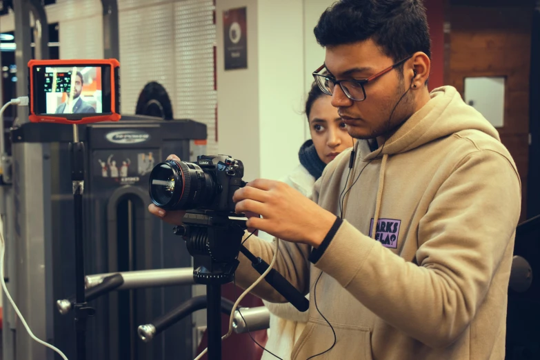 a man holding a camera while standing next to a girl