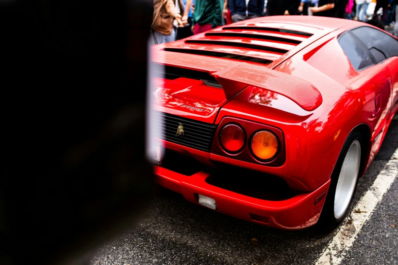 a red sports car with its hood slightly down on the street