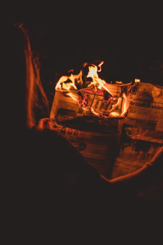 fire lit newspaper next to a black background
