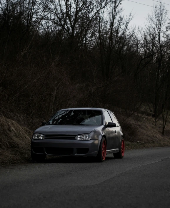 a car parked on the side of a road with red rims