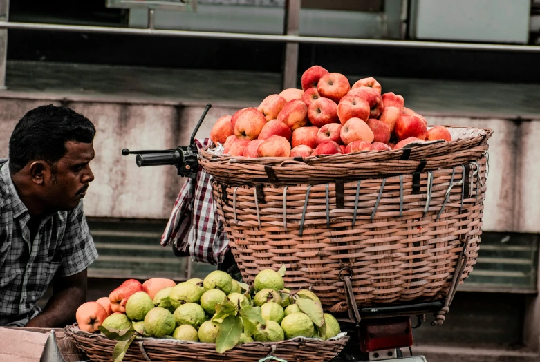 the man is sitting near his fruit stand