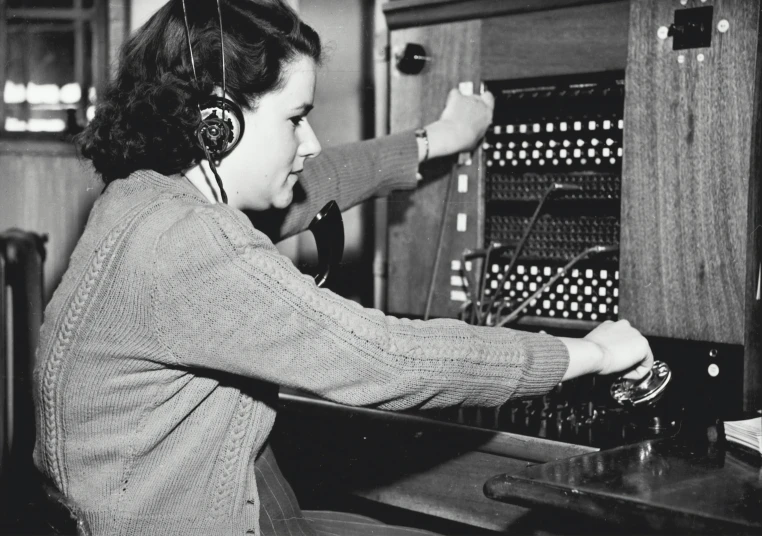 a lady wearing headphones sitting at a table with her back to the camera