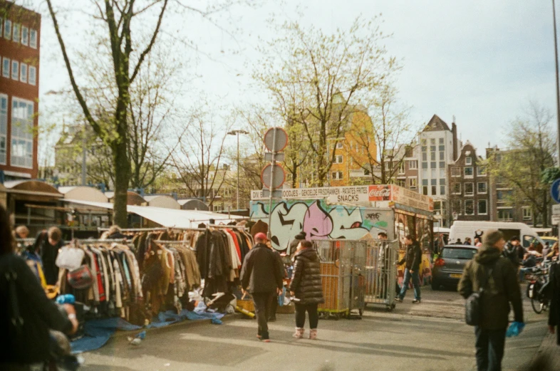 people walking on street next to many different types of clothing