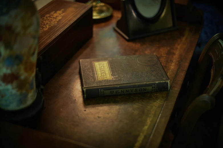 a book on top of a wooden table next to an alarm clock