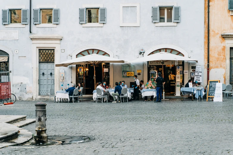 people are sitting and eating outside in front of buildings