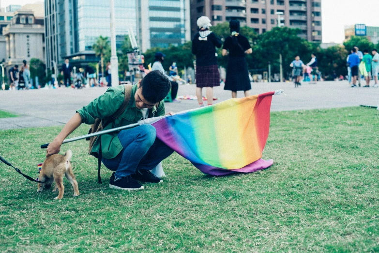 man holding a colorful kite and dog while kneeling down