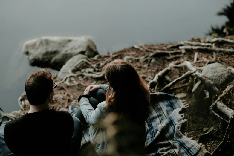 a couple of people are sitting on the rocks