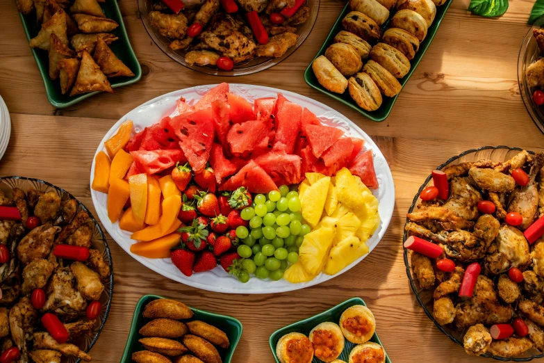 a wooden table with trays of food including fruit