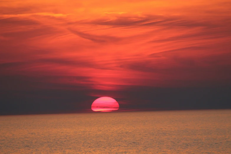 an orange sunset with white clouds and a red center